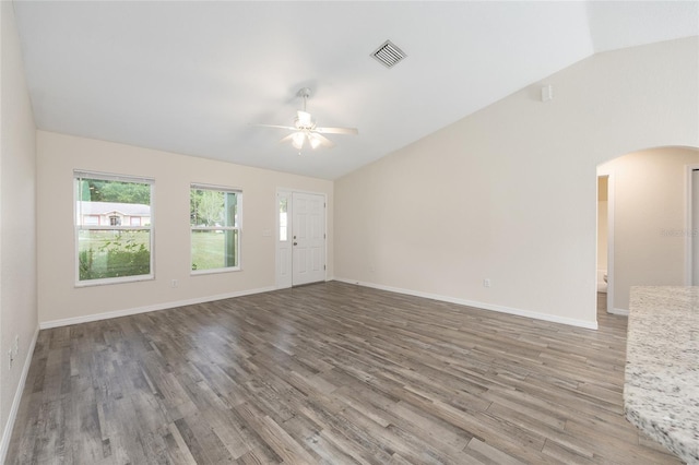 5425 Pecan Rd, Ocala, FL 34472 - unfurnished living room featuring lofted ceiling, a ceiling fan, arched walkways, wood finished floors, and baseboards