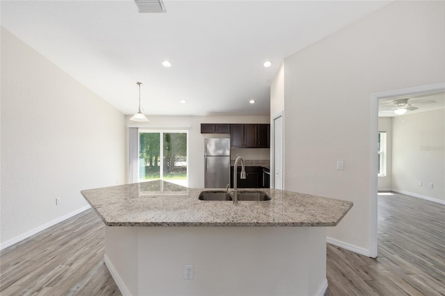 5425 Pecan Rd, Ocala, FL 34472 - kitchen with freestanding refrigerator, a sink, dark brown cabinets, light wood-type flooring, and a kitchen island with sink