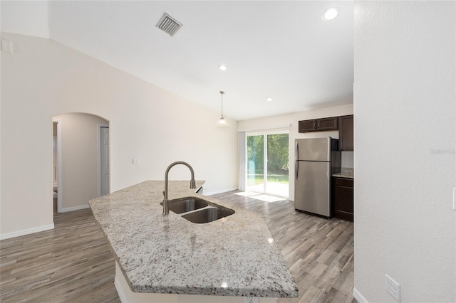 5425 Pecan Rd, Ocala, FL 34472 - kitchen featuring freestanding refrigerator, a sink, arched walkways, dark brown cabinetry, and light wood-style floors