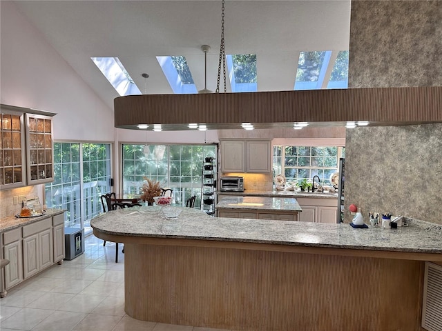 4305 SW 20th Ave, Ocala, FL 34471 - kitchen featuring a skylight, tasteful backsplash, light stone counters, and high vaulted ceiling