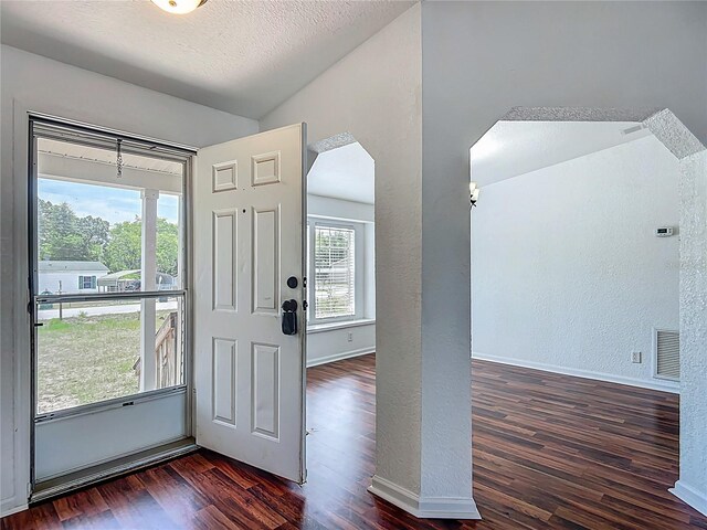 12352 SE 86th Ct, Belleview, FL 34420 - foyer entrance featuring vaulted ceiling, a textured wall, wood finished floors, baseboards, and arched walkways