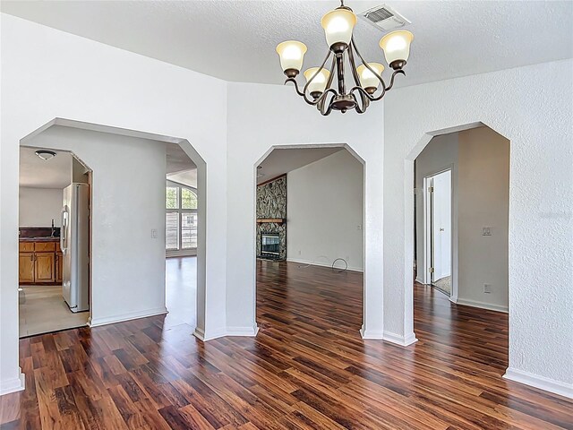 12352 SE 86th Ct, Belleview, FL 34420 - empty room with a chandelier, wood finished floors, baseboards, a textured ceiling, and a fireplace