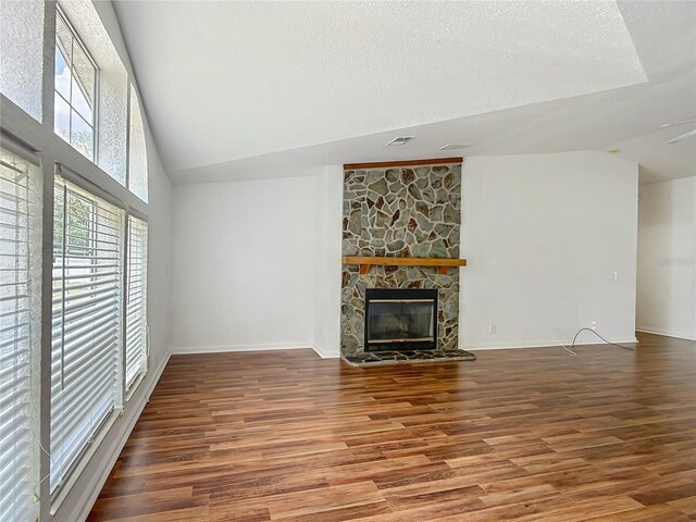 12352 SE 86th Ct, Belleview, FL 34420 - unfurnished living room featuring wood finished floors, a stone fireplace, baseboards, a textured ceiling, and high vaulted ceiling