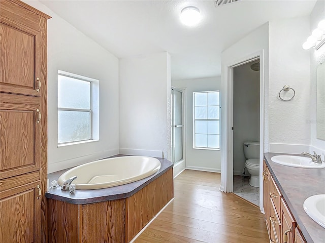 12352 SE 86th Ct, Belleview, FL 34420 - full bathroom featuring a stall shower, a bath, wood finished floors, toilet, and double vanity