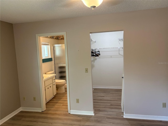 9801 SW 88th Ter Unit B, Ocala, FL 34481 - unfurnished bedroom with wood finished floors, a closet, ensuite bathroom, baseboards, and a textured ceiling