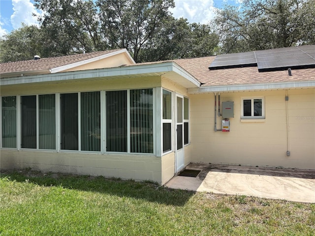 9801 SW 88th Ter Unit B, Ocala, FL 34481 - view of home's exterior featuring a sunroom, a shingled roof, concrete block siding, and roof mounted solar panels