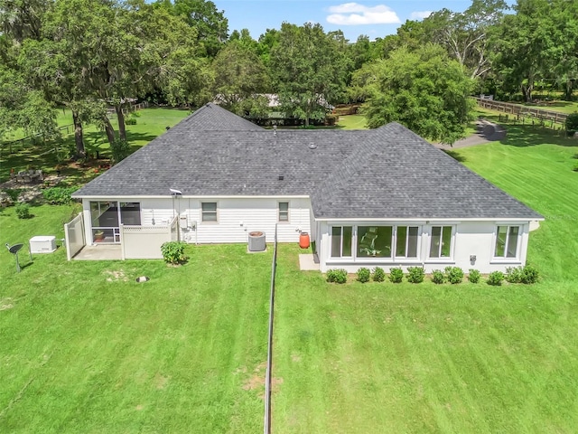 402 SW 127th Pl, Ocala, FL 34473 - rear view of property featuring a shingled roof, a sunroom, a lawn, and central AC unit