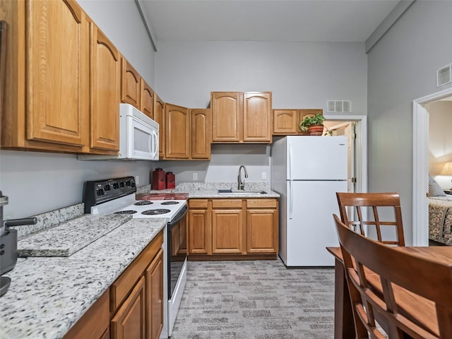 402 SW 127th Pl, Ocala, FL 34473 - kitchen featuring white appliances, a sink, light stone counters, and brown cabinetry