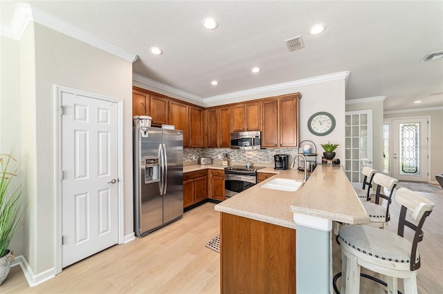 7263 SW 99th Cir, Ocala, FL 34481 - kitchen featuring appliances with stainless steel finishes, a peninsula, a kitchen bar, a sink, and crown molding