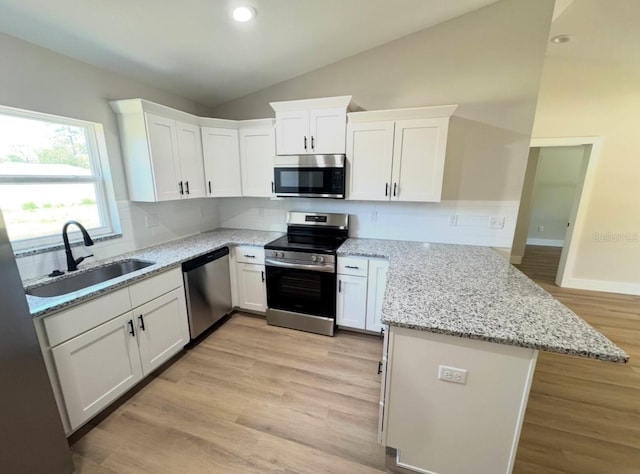 14425 SW 21st Pl, Ocala, FL 34481 - kitchen with appliances with stainless steel finishes, a sink, a peninsula, lofted ceiling, and light wood-type flooring