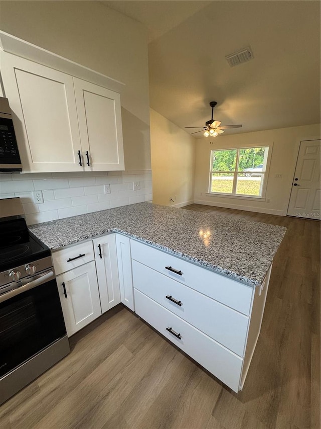 14425 SW 21st Pl, Ocala, FL 34481 - kitchen with appliances with stainless steel finishes, a peninsula, wood finished floors, and white cabinets