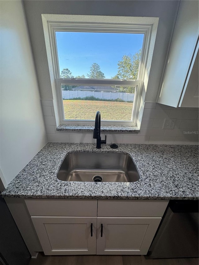 14425 SW 21st Pl, Ocala, FL 34481 - kitchen view of a sink, decorative backsplash, dishwasher, light stone counters, and white cabinets