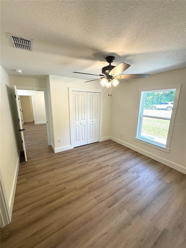 14425 SW 21st Pl, Ocala, FL 34481 - unfurnished bedroom featuring wood finished floors, baseboards, a textured ceiling, and a closet