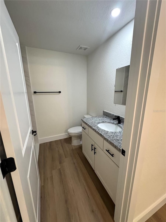 14425 SW 21st Pl, Ocala, FL 34481 - half bath featuring vanity, wood finished floors, toilet, baseboards, and a textured ceiling