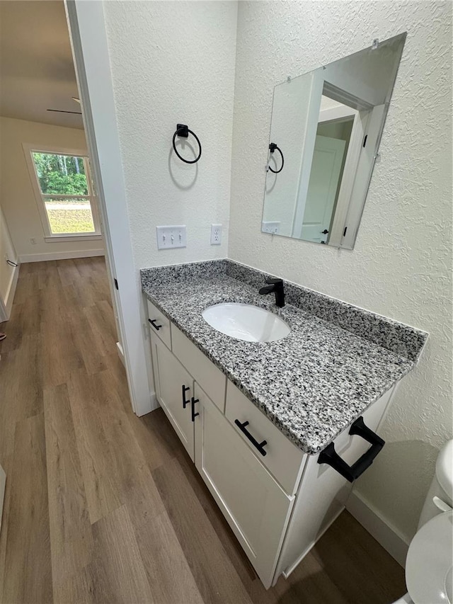 14425 SW 21st Pl, Ocala, FL 34481 - half bath with a textured wall, vanity, wood finished floors, toilet, and baseboards