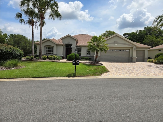 9459 SE 124th Loop, Summerfield, FL 34491 - mediterranean / spanish house featuring decorative driveway, stucco siding, an attached garage, and a front lawn