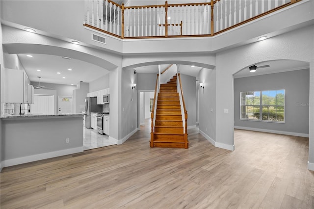 1628 SE 29th Ter, Ocala, FL 34471 - unfurnished living room with light wood-style floors, baseboards, a high ceiling, stairs, and recessed lighting
