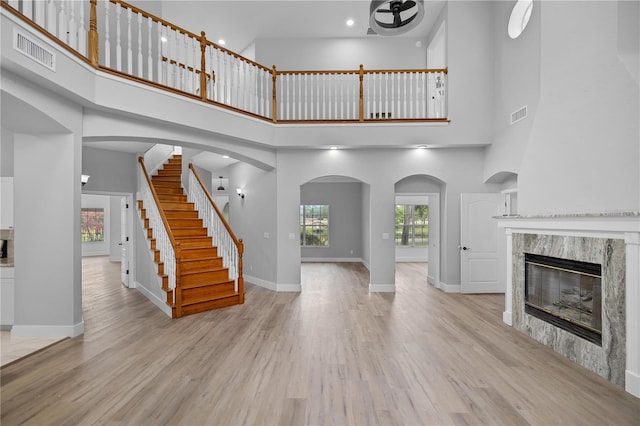 1628 SE 29th Ter, Ocala, FL 34471 - unfurnished living room with a towering ceiling, a high end fireplace, wood finished floors, ceiling fan, and baseboards