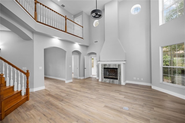 1628 SE 29th Ter, Ocala, FL 34471 - unfurnished living room with a high ceiling, wood finished floors, arched walkways, a high end fireplace, and baseboards