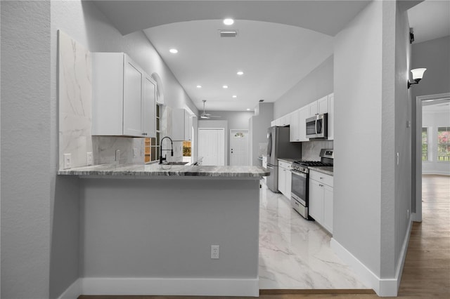 1628 SE 29th Ter, Ocala, FL 34471 - kitchen with stainless steel appliances, tasteful backsplash, a peninsula, baseboards, and white cabinets