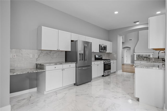 1628 SE 29th Ter, Ocala, FL 34471 - kitchen featuring appliances with stainless steel finishes, a sink, arched walkways, light stone counters, and tasteful backsplash