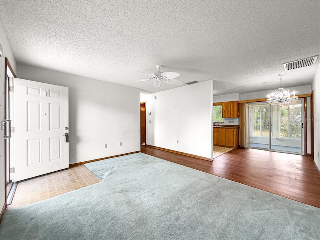10520 SW 85th Ter, Ocala, FL 34481 - unfurnished living room with carpet flooring, a chandelier, ceiling fan, baseboards, and a textured ceiling