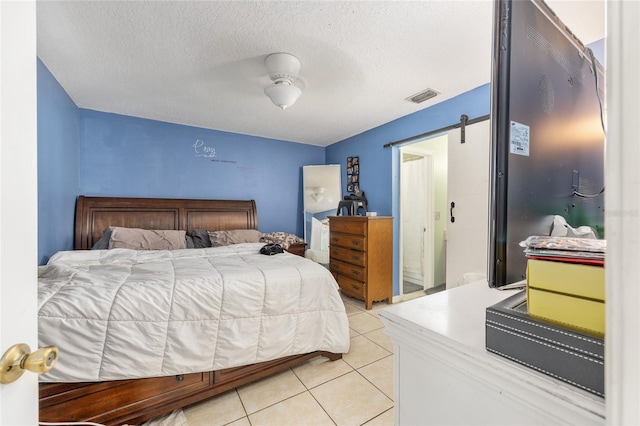 3800 NE 24th Ct, Ocala, FL 34479 - bedroom with light tile patterned floors, a barn door, and a textured ceiling