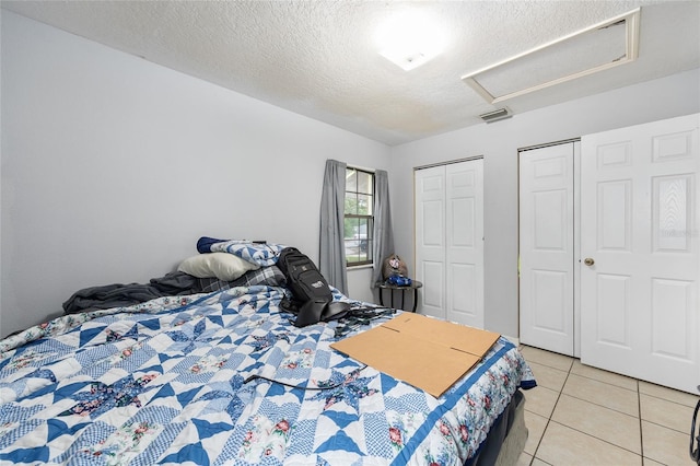 3800 NE 24th Ct, Ocala, FL 34479 - bedroom with attic access, light tile patterned floors, a textured ceiling, and multiple closets