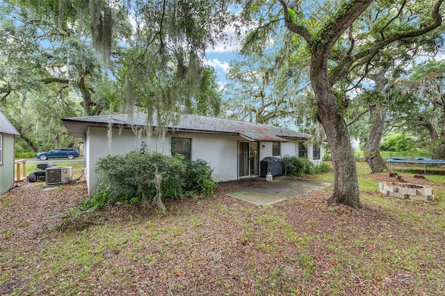 3800 NE 24th Ct, Ocala, FL 34479 - rear view of house featuring stucco siding, central air condition unit, a trampoline, and a patio area