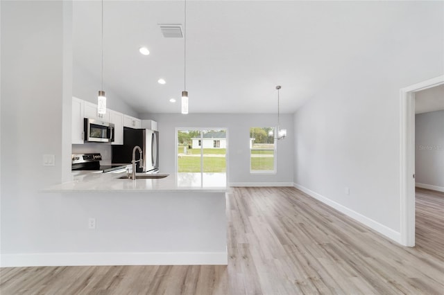 2693 SW 147th Ter, Ocala, FL 34481 - kitchen with appliances with stainless steel finishes, lofted ceiling, light wood-type flooring, white cabinetry, and decorative light fixtures