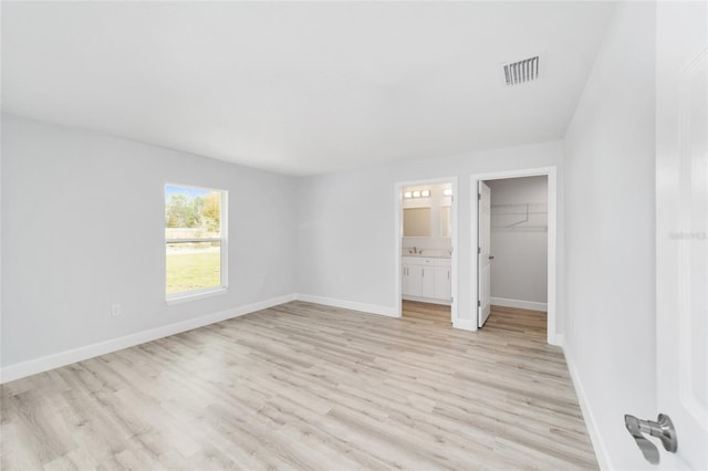 2693 SW 147th Ter, Ocala, FL 34481 - unfurnished bedroom with light wood-style floors, baseboards, a spacious closet, a closet, and connected bathroom