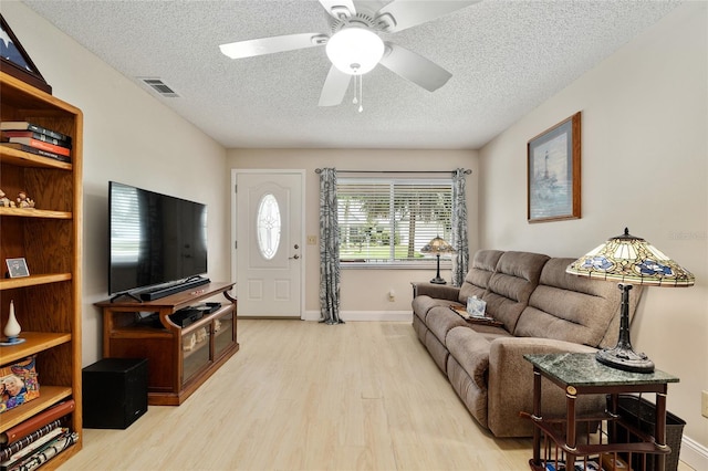 9290 SW 89th Ter Unit D, Ocala, FL 34481 - living room featuring light wood-style flooring, a textured ceiling, ceiling fan, and baseboards