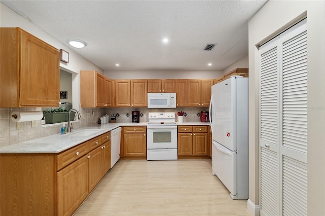 9290 SW 89th Ter Unit D, Ocala, FL 34481 - kitchen featuring white appliances, a sink, light wood-style flooring, tasteful backsplash, and light stone countertops