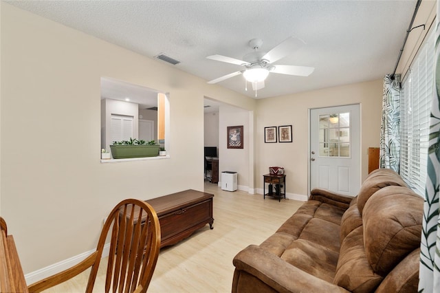 9290 SW 89th Ter Unit D, Ocala, FL 34481 - living room featuring light wood-style flooring, baseboards, a ceiling fan, and a textured ceiling
