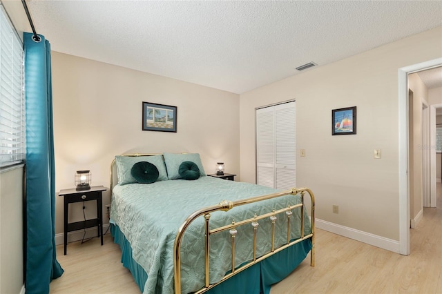 9290 SW 89th Ter Unit D, Ocala, FL 34481 - bedroom featuring light wood finished floors, a closet, baseboards, and a textured ceiling