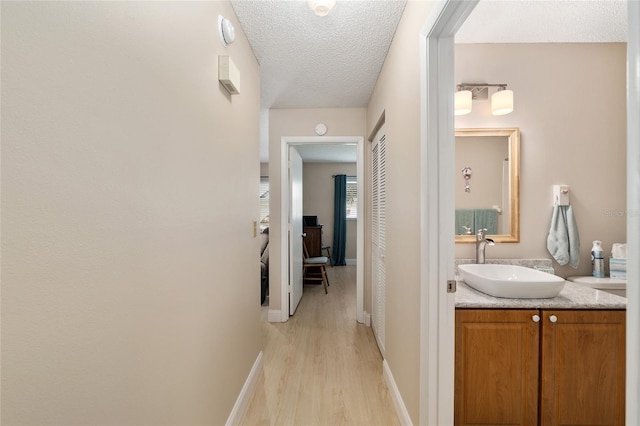 9290 SW 89th Ter Unit D, Ocala, FL 34481 - hallway featuring a sink, light wood-style flooring, baseboards, and a textured ceiling