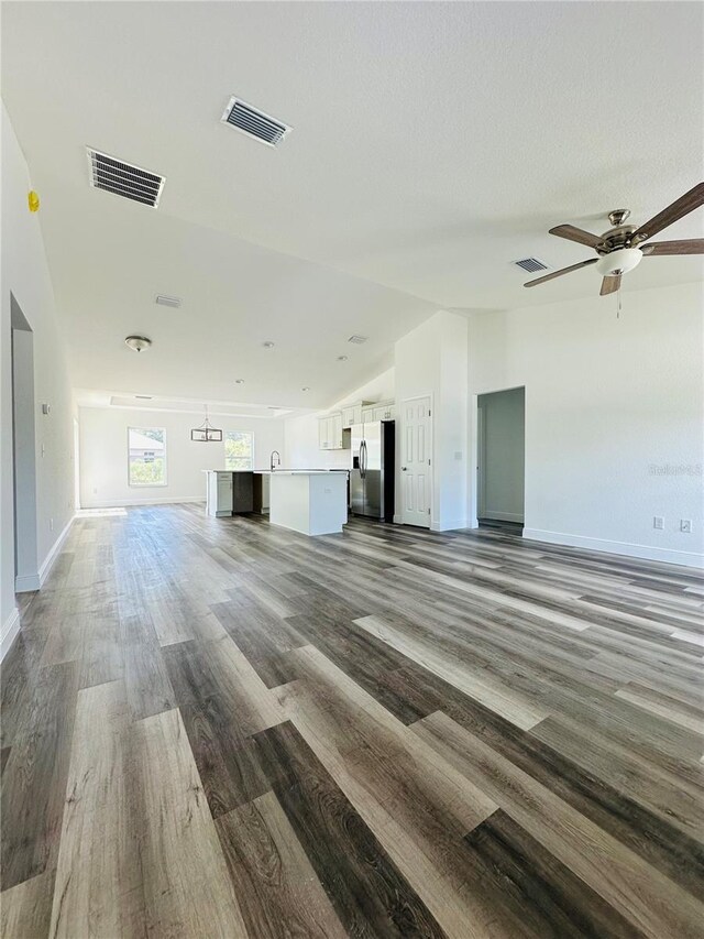 12282 SW 80th St, Dunnellon, FL 34432 - unfurnished living room with lofted ceiling, wood finished floors, baseboards, ceiling fan, and a sink