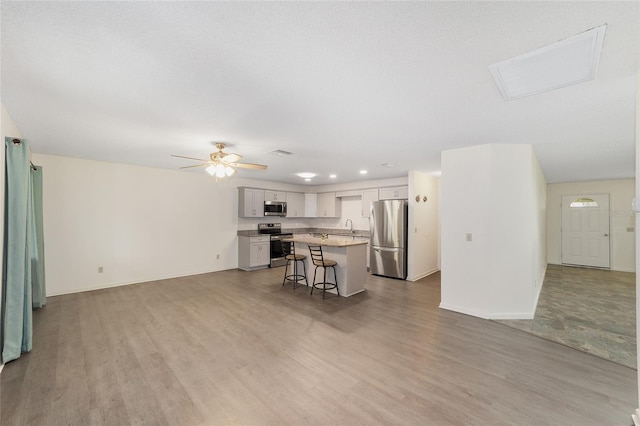 8998 SW 94th St Unit D, Ocala, FL 34481 - kitchen featuring appliances with stainless steel finishes, open floor plan, a sink, a kitchen bar, and light wood-style floors