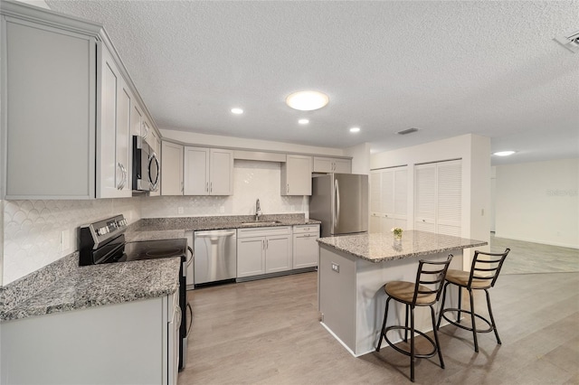 8998 SW 94th St Unit D, Ocala, FL 34481 - kitchen with appliances with stainless steel finishes, a breakfast bar area, a kitchen island, a textured ceiling, and a sink