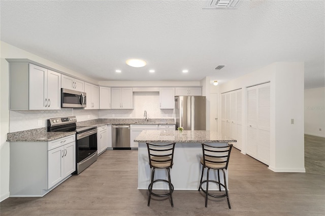 8998 SW 94th St Unit D, Ocala, FL 34481 - kitchen with stainless steel appliances, light wood-type flooring, a kitchen breakfast bar, light stone counters, and a kitchen island