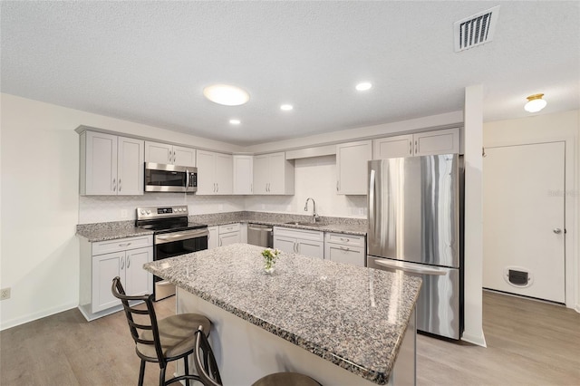 8998 SW 94th St Unit D, Ocala, FL 34481 - kitchen with appliances with stainless steel finishes, light wood finished floors, a kitchen breakfast bar, light stone counters, and recessed lighting