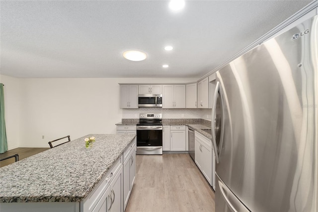 8998 SW 94th St Unit D, Ocala, FL 34481 - kitchen featuring appliances with stainless steel finishes, light wood-style floors, a center island, light stone counters, and recessed lighting