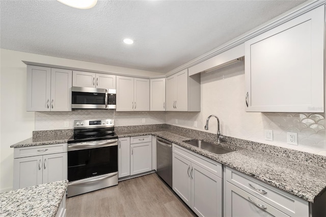 8998 SW 94th St Unit D, Ocala, FL 34481 - kitchen with appliances with stainless steel finishes, a sink, light wood-style floors, decorative backsplash, and recessed lighting