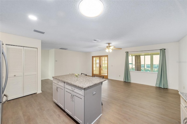 8998 SW 94th St Unit D, Ocala, FL 34481 - kitchen with ceiling fan, light wood-type flooring, a center island, a textured ceiling, and open floor plan