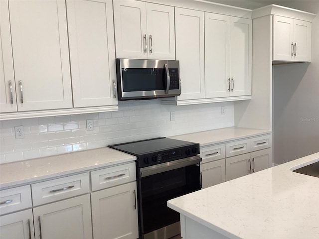 10540 SW 49th Avenue Rd, Ocala, FL 34476 - kitchen featuring stainless steel microwave, black range with electric cooktop, white cabinetry, backsplash, and light stone countertops