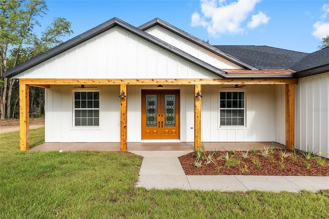 8200 SW 125th Court Rd, Dunnellon, FL 34432 - view of front of home with roof with shingles, a front yard, a ceiling fan, a porch, and french doors