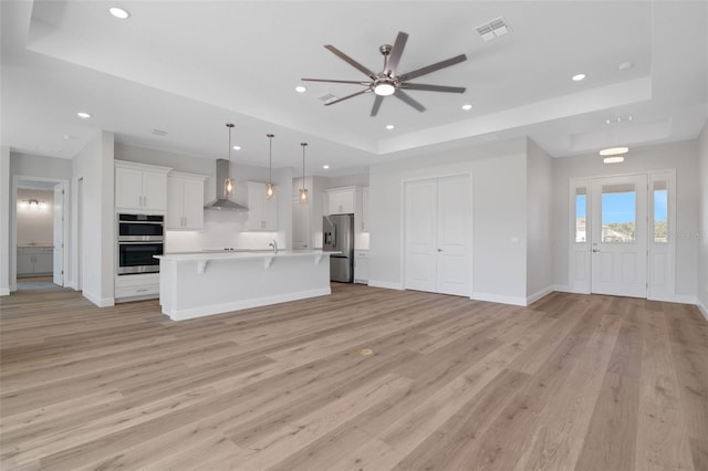 2050 NW 79th Loop, Ocala, FL 34475 - kitchen featuring a raised ceiling, stainless steel appliances, wall chimney exhaust hood, open floor plan, and a ceiling fan