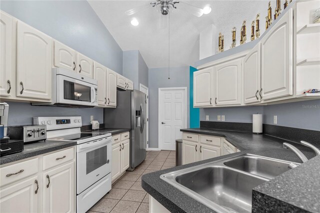 2698 SW 186th Ct, Dunnellon, FL 34432 - kitchen featuring white appliances, light tile patterned flooring, dark countertops, white cabinets, and vaulted ceiling