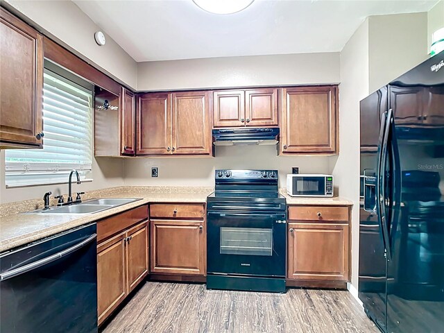 1520 NE 17th Ave, Ocala, FL 34470 - kitchen with black appliances, under cabinet range hood, a sink, light wood-style floors, and light countertops