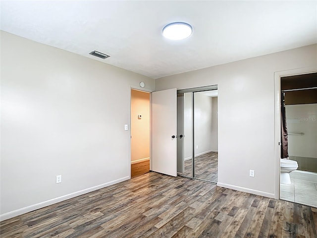 1520 NE 17th Ave, Ocala, FL 34470 - unfurnished bedroom with wood finished floors, baseboards, and ensuite bathroom